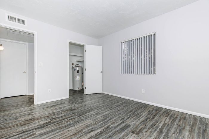 Bright and airy room with sleek modern flooring, large window with blinds, and fresh neutral walls.