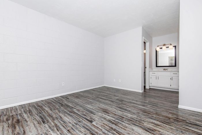 Bright and spacious room with elegant wood-style flooring, featuring a modern vanity area and sleek lighting.
