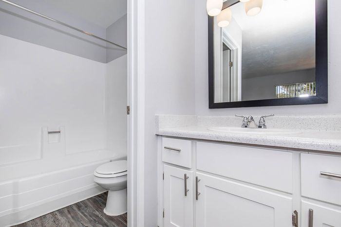 Bright and modern bathroom with elegant white cabinetry, sleek countertop, and large mirror, perfect for a stylish apartment living.