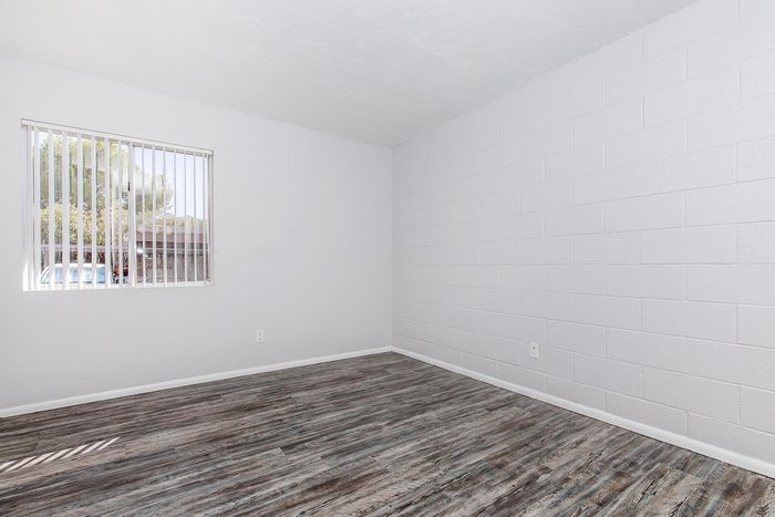 Bright and inviting room with sleek wooden flooring and a sunny window view, perfect for a cozy living space.