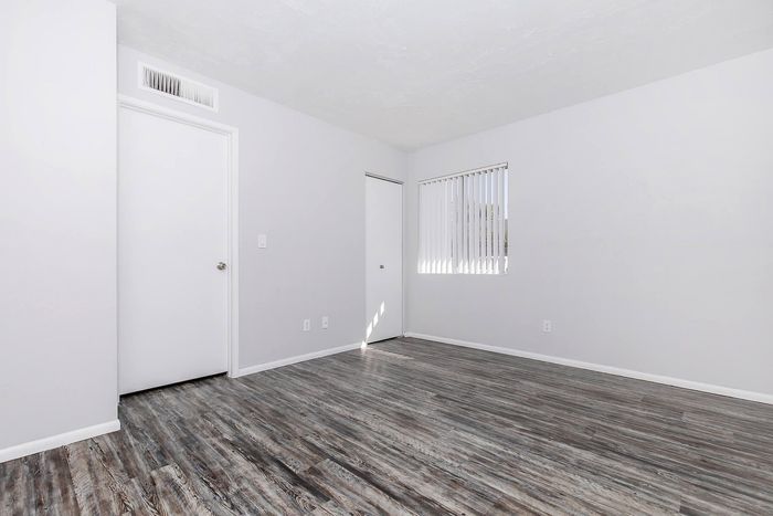 Bright, airy room with modern gray wood flooring and sleek white walls, perfect for customization.