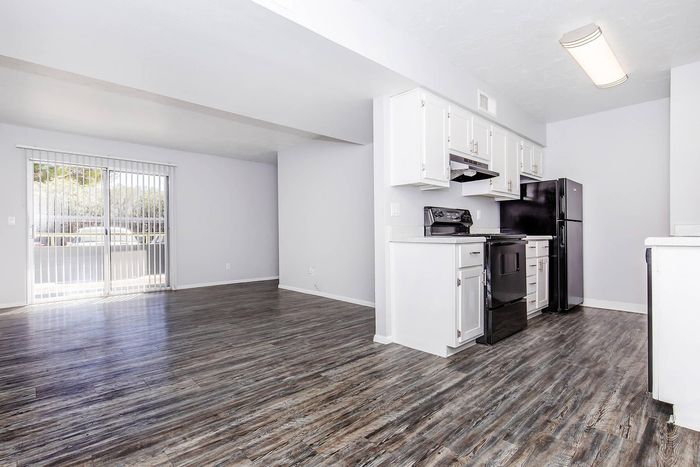 Bright, open-concept apartment with modern kitchen and elegant wood flooring, featuring large windows that invite natural light.