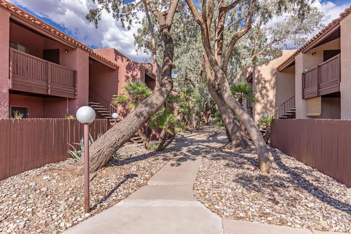 Charming apartment complex with earthy tones, surrounded by lush greenery and scenic pathways, perfect for nature lovers.