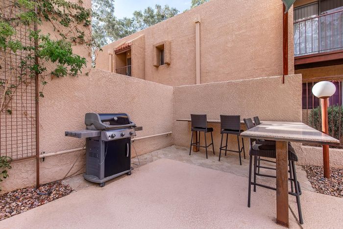 Charming outdoor patio with a modern grill, stylish bar seating, and warm terracotta walls, perfect for entertaining.