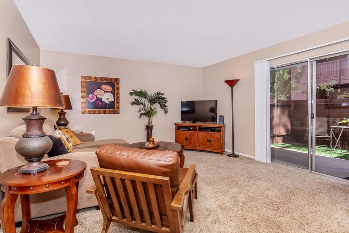 Inviting living room with plush seating, elegant decor, and natural light from a sliding glass door leading to a quaint garden view.