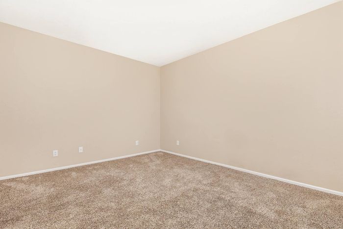 Bright and spacious room with fresh beige walls and cozy carpeting, perfect for personalizing your dream space.