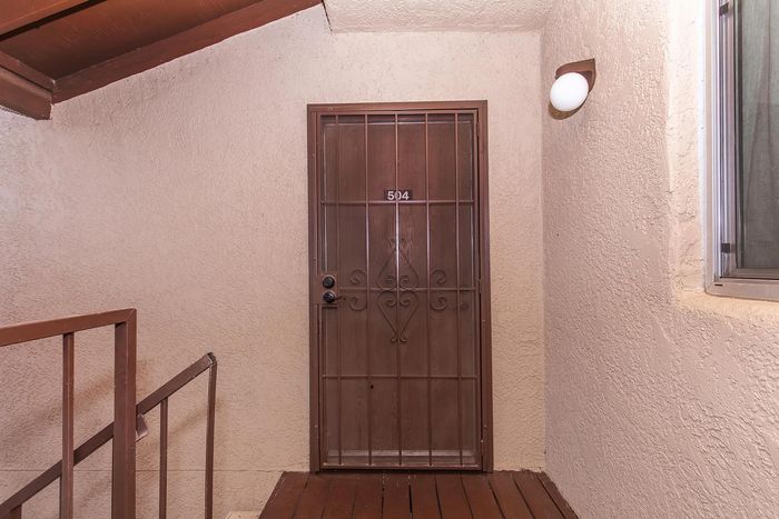 Inviting apartment entrance with elegant wrought iron door and warm, textured walls.