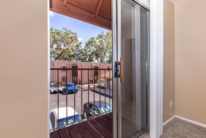 Charming apartment balcony with a view of lush trees and a serene parking area, perfect for relaxing in tranquility.