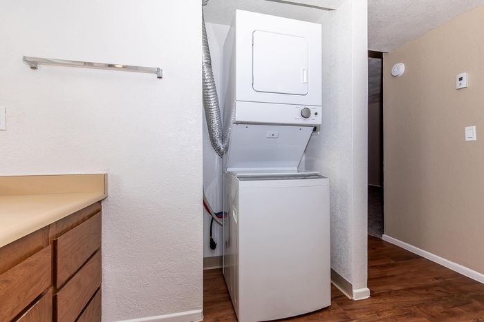 Compact laundry nook featuring modern stackable washer and dryer set in a cozy apartment space.