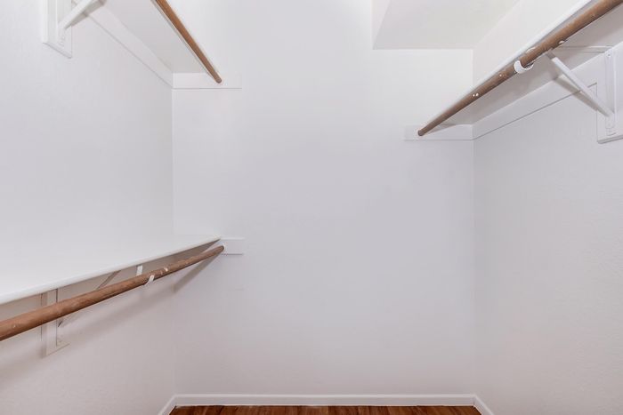 Spacious walk-in closet with ample hanging space and elegant wooden flooring, offering organization and style.