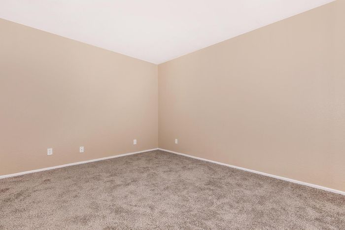 Inviting corner of a room featuring soft beige walls and plush carpet, offering a neutral palette and cozy atmosphere.
