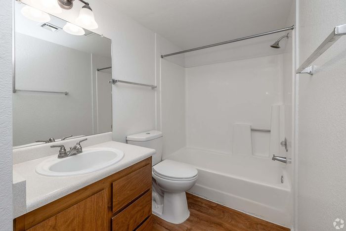 Contemporary bathroom with elegant wooden cabinetry, spacious mirror, and inviting bathtub in a bright, airy setting.