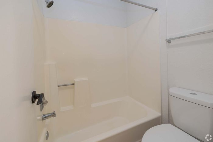 Modern bathroom with a sleek white bathtub and a compact toilet, showcasing a clean and minimalist design.