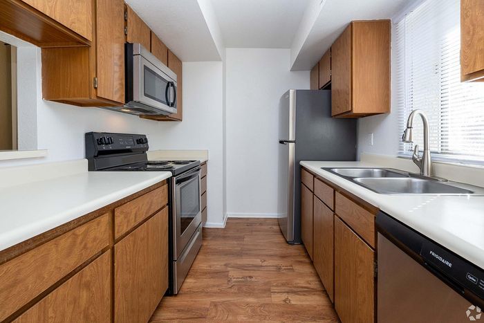 Chic galley kitchen with stainless steel appliances, sleek countertops, and warm wooden cabinetry, perfect for culinary creativity.
