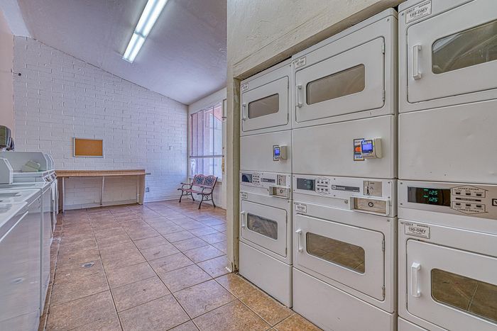 Bright and spacious laundry room with stacked dryers, ample natural light, and a convenient seating area.