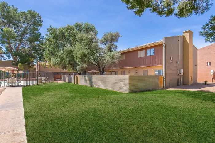 Spacious apartment complex with lush green lawn, shaded outdoor seating, and vibrant trees, creating a serene living environment.