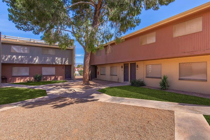 Charming apartment complex with modern exterior, shady walkways, and lush greenery, offering a welcoming and tranquil living environment.