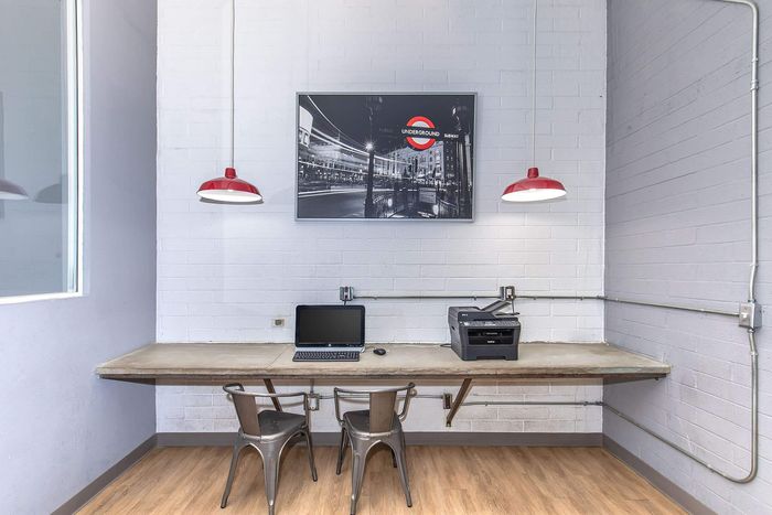 Contemporary home office corner with sleek metal chairs, industrial lighting, and modern equipment.