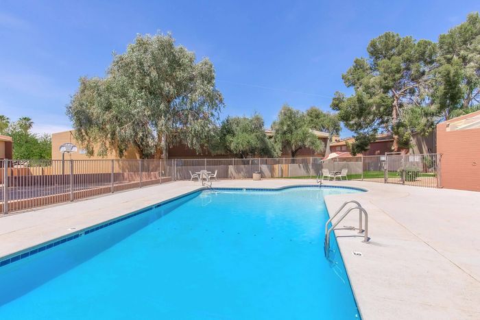 Inviting outdoor swimming pool surrounded by lush greenery and comfortable seating, perfect for relaxation under clear blue skies.