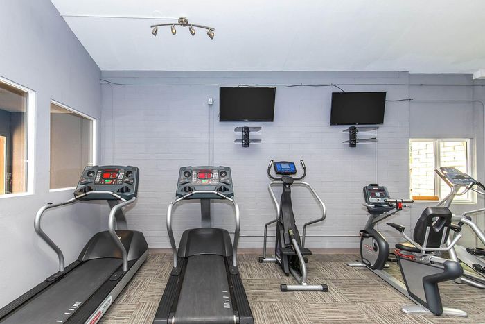 Modern fitness room with state-of-the-art treadmills, exercise bikes, and wall-mounted TVs, perfect for a dynamic workout experience.