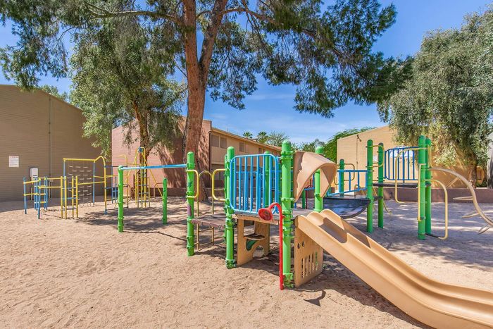 Inviting outdoor playground with colorful slides and climbing structures, nestled under lush trees for shaded fun.