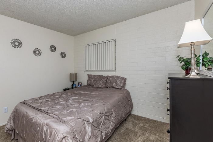 Cozy bedroom featuring a soft taupe bed, modern decor, and warm lighting, perfect for relaxation.