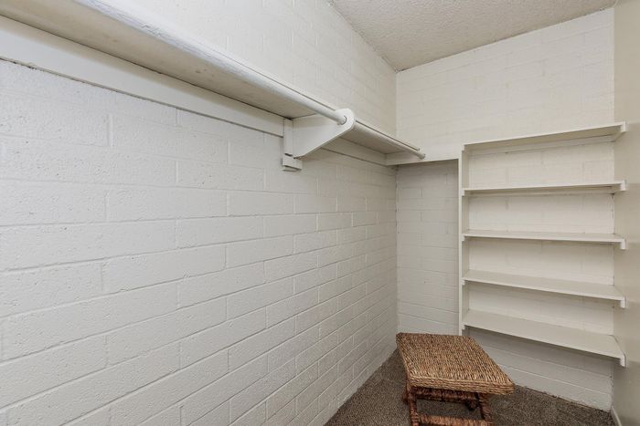 Spacious walk-in closet featuring modern white shelving and ample hanging space, perfect for organizing a stylish wardrobe.