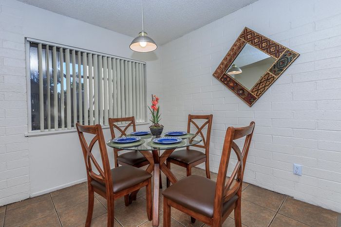 Charming dining area with a round glass table and stylish wooden chairs, enhanced by elegant decor and natural light.