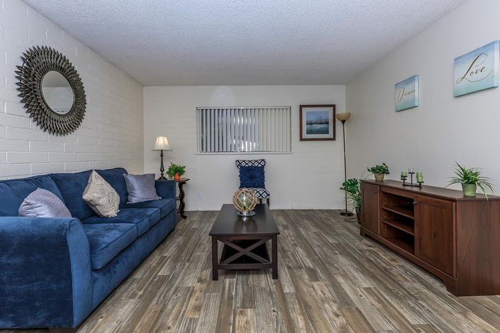 Inviting living room featuring a plush blue couch, elegant wooden coffee table, and modern decor with natural light and stylish wooden flooring.