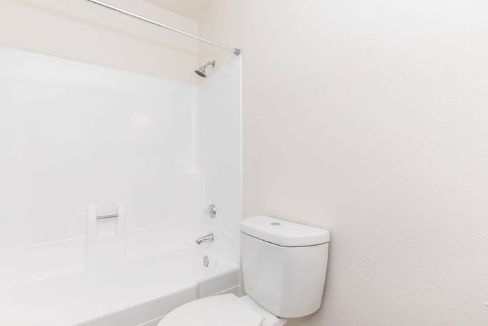 Bright and modern bathroom with pristine white fixtures, featuring a sleek bathtub and compact toilet.