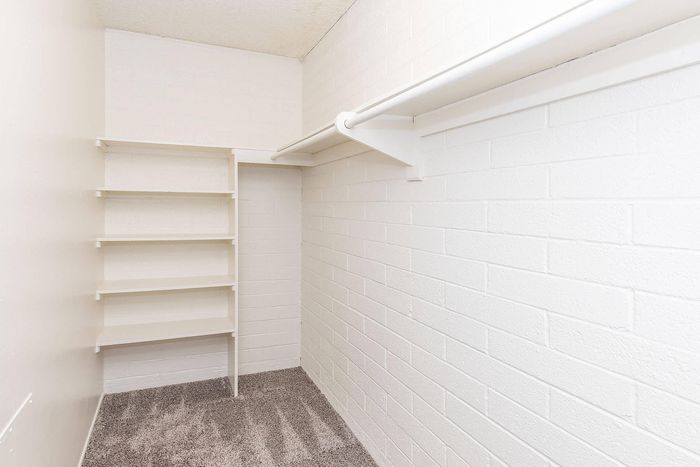 Bright and spacious walk-in closet with built-in shelves and hanging rail, offering ample storage and organization options.