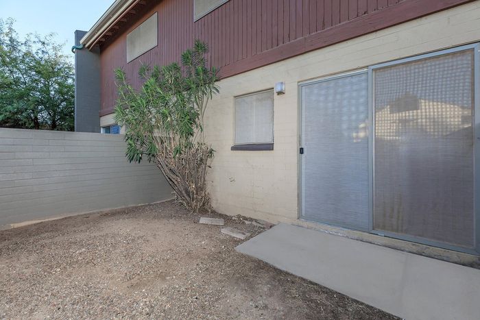 Charming outdoor space with a private patio, textured wall, and lush greenery, perfect for relaxation and entertainment.