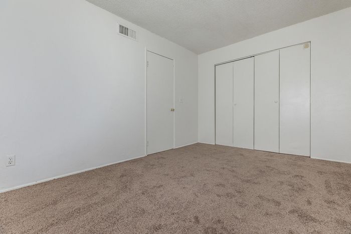 Inviting bedroom with plush carpet and ample natural light, featuring a spacious closet for convenient storage.