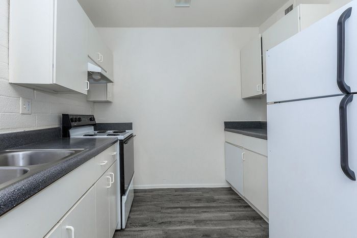 Modern galley kitchen with sleek white cabinetry and dark countertops, offering a stylish and functional cooking space.