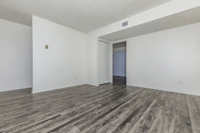 Bright and spacious room with sleek gray wooden flooring, offering a blank canvas for personalized design.