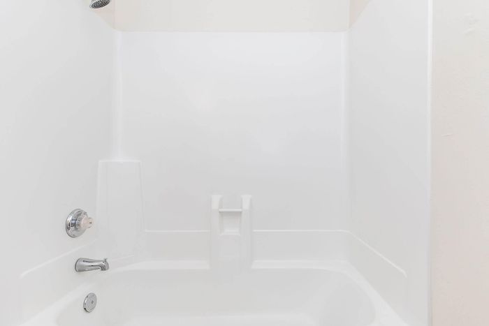 Pristine white bathtub with modern fixtures, perfect for a contemporary bathroom setting.
