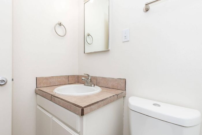 Bright, modern bathroom featuring a sleek vanity with tiled countertop and a stylish mirror on a pristine white wall.