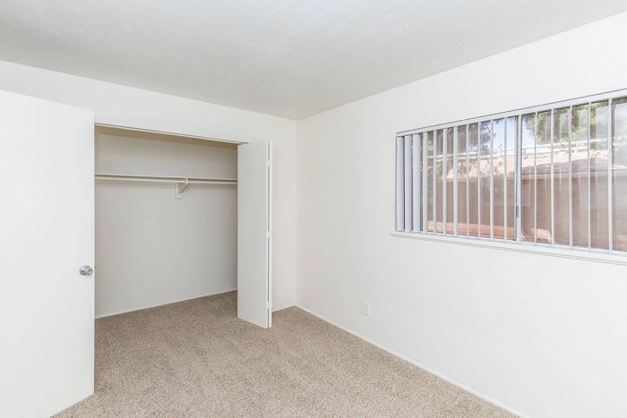 Bright bedroom with large window and spacious closet, offering a minimalist and inviting atmosphere.