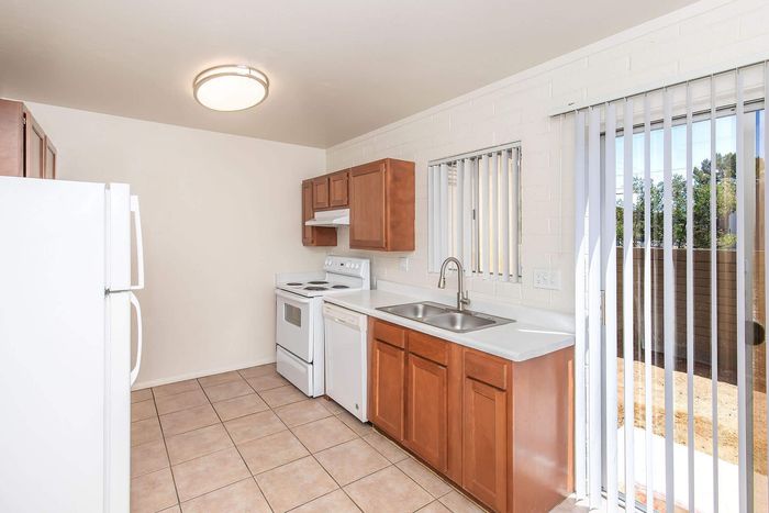 Bright and inviting kitchen with sleek appliances, wooden cabinetry, and plentiful natural light from sliding glass doors.