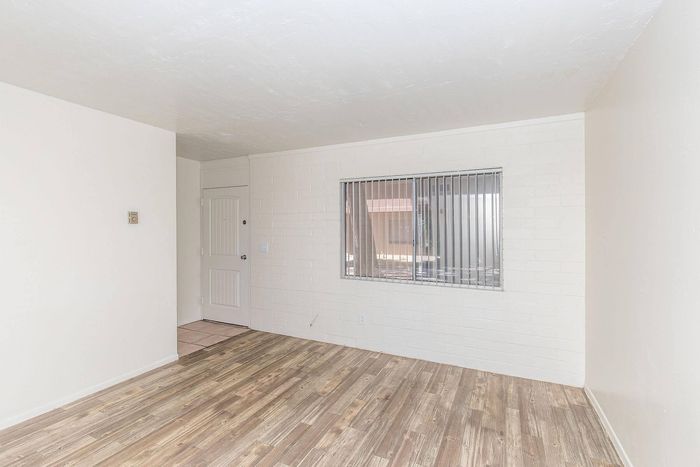Bright and spacious room with elegant wood flooring and large window for natural light.
