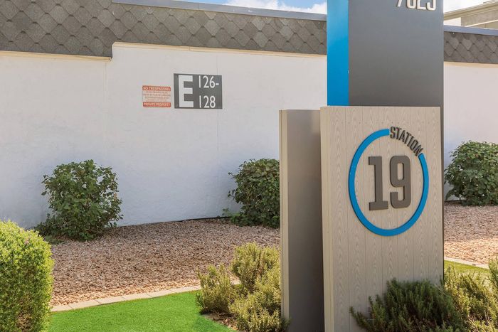 Inviting entrance at Station 19 with modern signage, lush greenery, and numbered building access.
