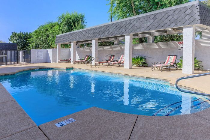 Inviting outdoor pool with lounge chairs, surrounded by lush greenery and modern pergola for a relaxing retreat.