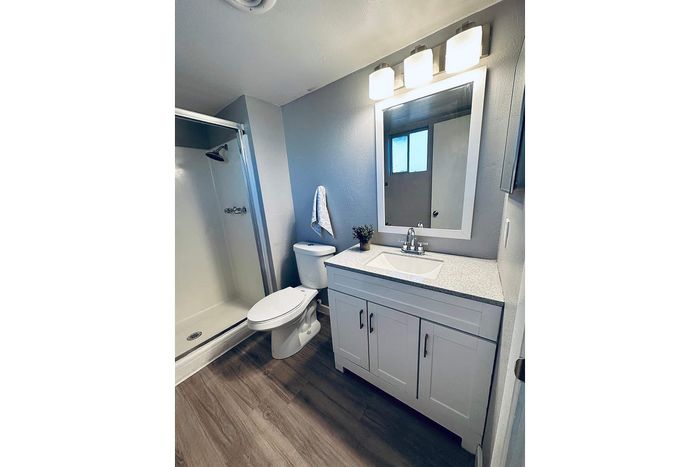 Modern bathroom with elegant fixtures, featuring a sleek vanity, spacious shower, and stylish wood flooring.