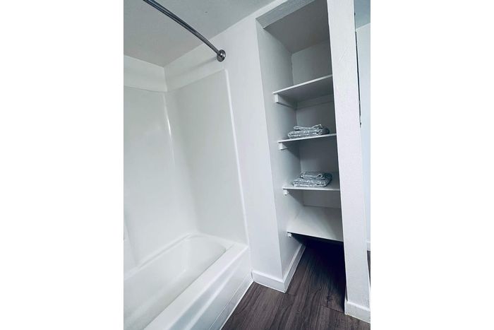 Modern bathroom with sleek white bathtub and convenient built-in shelves, offering a contemporary and practical design.