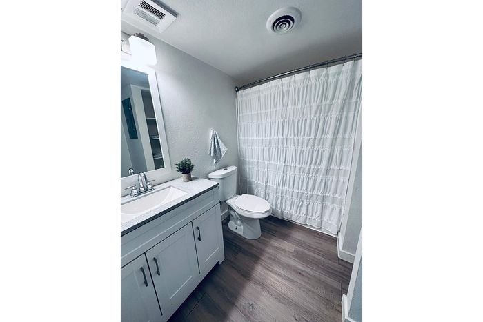 Modern bathroom with elegant white cabinetry, sleek countertop, and stylish wooden flooring.