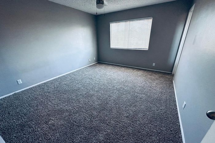 Spacious bedroom with plush carpeting and ample natural light from a large window, perfect for creating a cozy retreat.