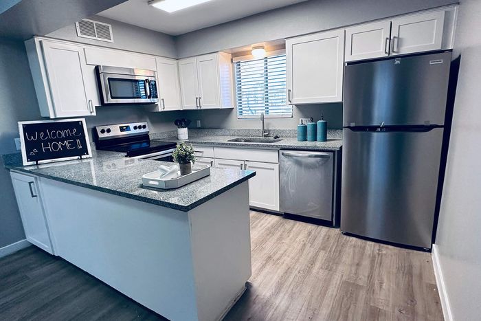 Modern kitchen with stainless steel appliances, granite countertops, and white cabinetry, featuring a welcoming atmosphere.