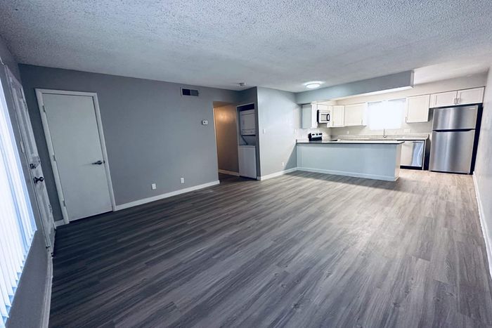 Spacious open-concept apartment featuring modern kitchen with stainless steel appliances and sleek laminate flooring.