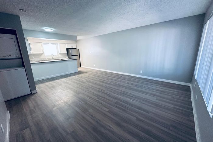 Bright and spacious open-concept living area with modern kitchen and sleek appliances, featuring elegant wood flooring.