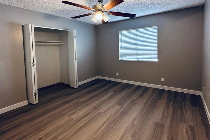 Inviting bedroom featuring modern wood flooring, ample closet space, and refreshing natural light from large window.